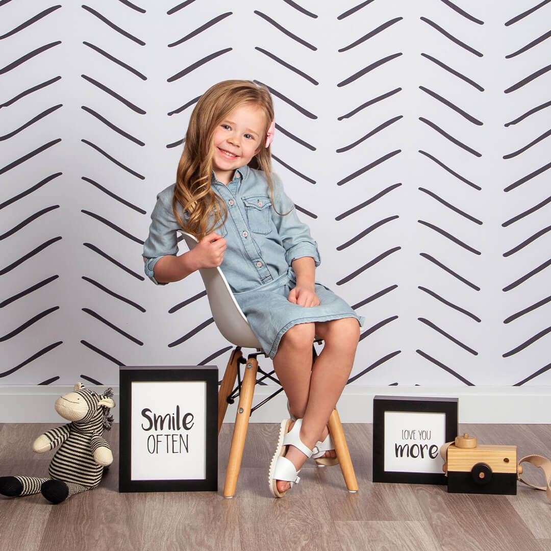 Girl sitting on a chair with props posing for photos on Herringbone background