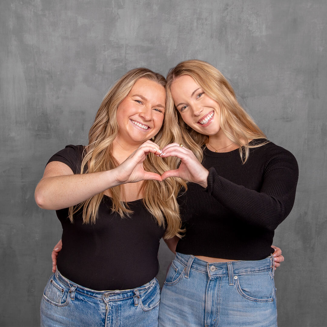 Two women making a heart with their hands at a best friend photoshoot