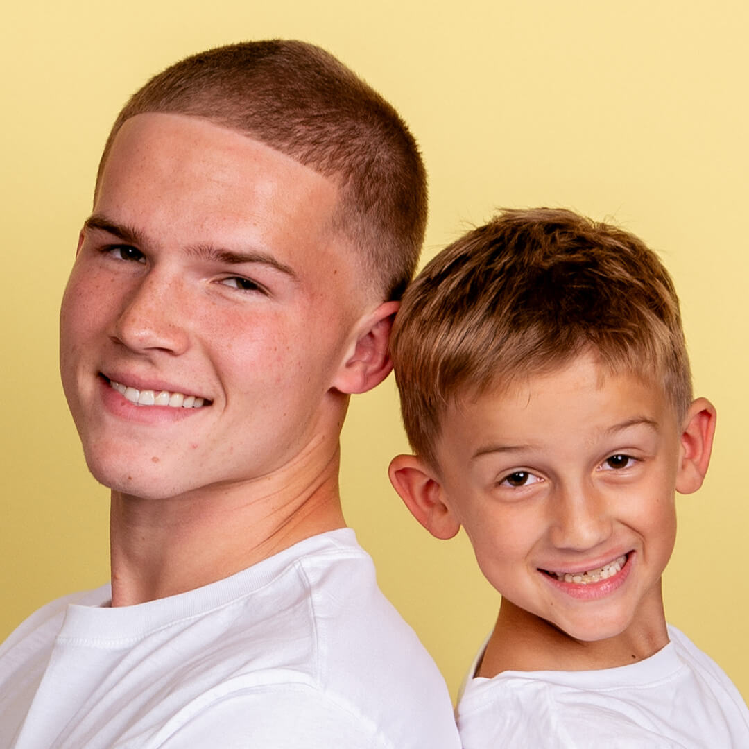 Brothers posing for candid photos on a yellow background.