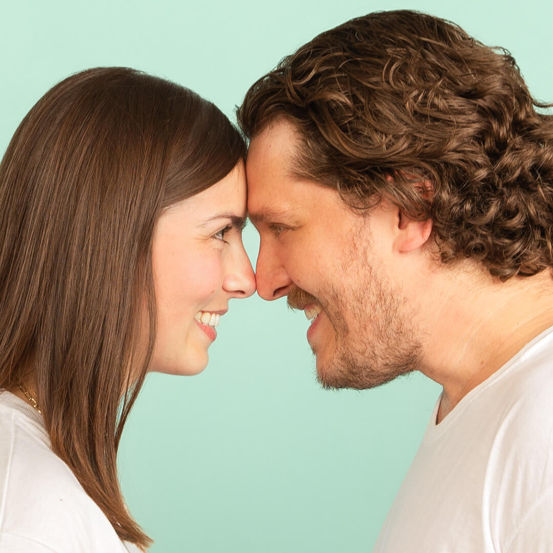 Couple posing for candid photos on a blue background.