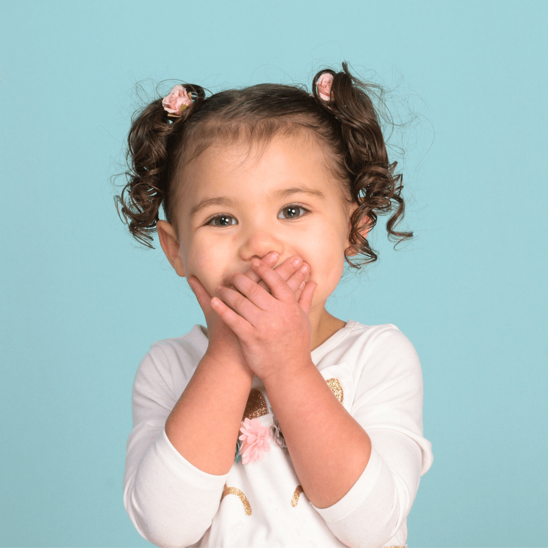 Girl holding her hands in front of her mouth, posing for pictures.